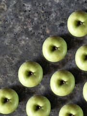 Pattern of green apples on black concrete background with copy space. Granny smith. Fresh fruits background.