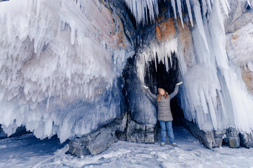 Adventure extreme woman tourist background of frozen grotto and pure ice winter Lake Baikal