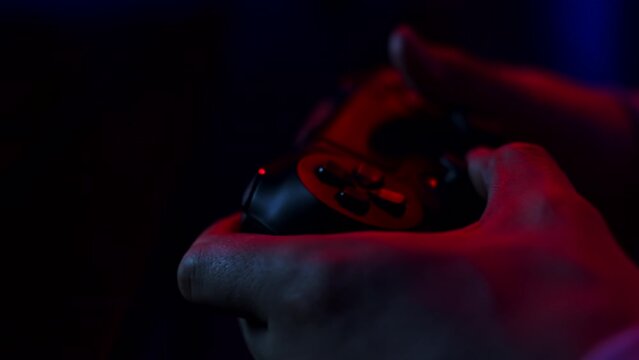 Closeup man's hands holding gamepad and pressing buttons while playing video games on console. Person plays video games on game console with gamepad