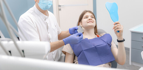 Happy young brunette woman at dentist checks her smile teeth