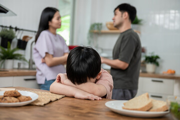 Young little Asian kid feel sad upset, boring while parent fighting arguing or quarrel, sad little boy crying with psychological problem caused by mom and dad family conflicts or violence concept.