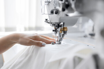 Seamstress in the workplace. close-up view of hands sewing some clothes. sewing machine