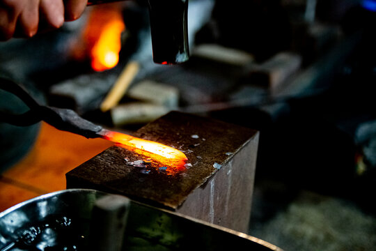 Japanese blacksmith is hammering the hot red steel to make a small Japanese sword.