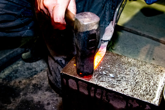 Japanese blacksmith is hammering the hot red steel to make a small Japanese sword.