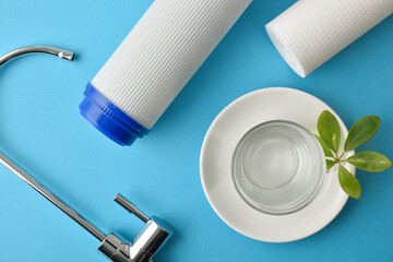 Glass of osmosis filtered water and filters on blue table