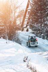 tractor removing snow in mountain suburban area. bulldozer is de-icing roads in countryside