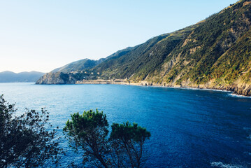 Fototapeta premium Beautiful seascape with blue sky, smooth water surface and rocky cliffs in Liguria coastal area. Popular italian travel destination.