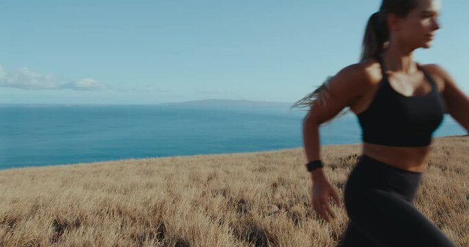 Slow motion of woman running in golden field above the ocean, healthy active lifestyle