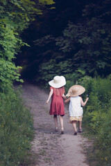 Children running down dark path into woods. Dangerous walks in park and forest