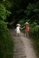 Fototapeta na wymiar Children running down dark path into woods. Dangerous walks in park and forest