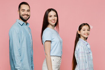 Side view young happy cheerful fun parents mom dad with child kid daughter teen girl in blue clothes look camera isolated on plain pastel light pink background Family day parenthood childhood concept