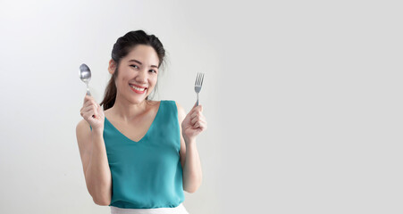 Asian beautiful woman are holding spoon and fork to be ready for eating with smile face and hungry