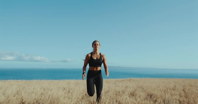 Slow motion of woman running in golden field above the ocean, healthy active lifestyle