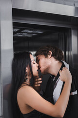 Sexy couple in formal wear kissing near elevator.