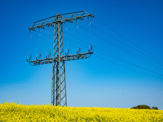 Strommast Energie mit Rapsfeld im Frühling
