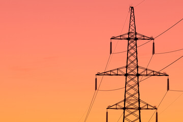 Background, view or scene of steel tower of electric main or electricity transmission line with the wires silhouette on yellow, orange and red background of sunset or sunrise sky