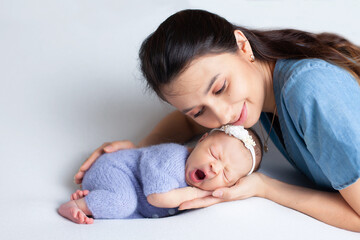 Beautiful young mother with a newborn daughter in a diaper on a white background. Motherhood....