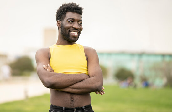 Gay man with multicolored shadows on his eyelids looking at the camera. Happy african transgender man outdoors - concept makeup man -