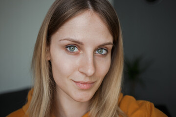 Fototapeta premium A girl in a yellow sweatshirt with green eyes looks at the camera