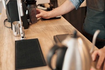 Close up of barista hand installs a container with coffee beans in the coffee machine