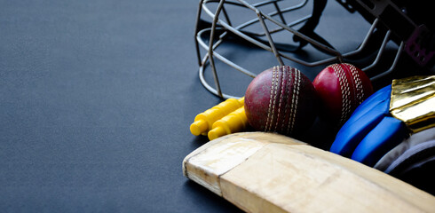 Old training cricket sport equipments on dark floor, leather ball, wickets, helmet, gloves and...