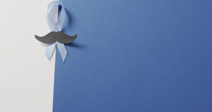 Video of paper moustache and pale blue prostate cancer ribbon on white and blue background