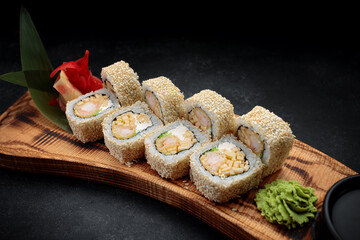 Roll Ebi Ringo with tiger shrimp, cream cheese, apple and tobiko, on a wooden board, on a dark background