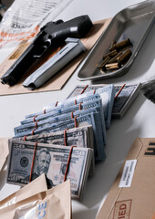Money and weapons in crime lab for investigation, conceptual image