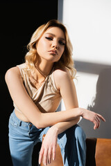 sensual woman looking at camera while posing on black and white background with shadows.