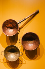 three antique pan, brass and copper holes on a yellow background