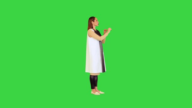 Robotic girl stands operating virtual monitors on a Green Screen, Chroma Key.
