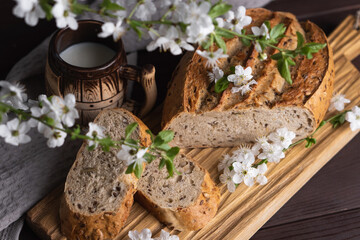 Pieces of fresh homemade rye bread with clay mug of milk on wooden cutting board. Healthy breakfast
