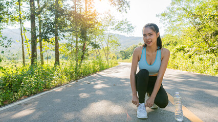 Asian woman tying her shoes before going for a run in the park. Outdoor jogging fitness concept.