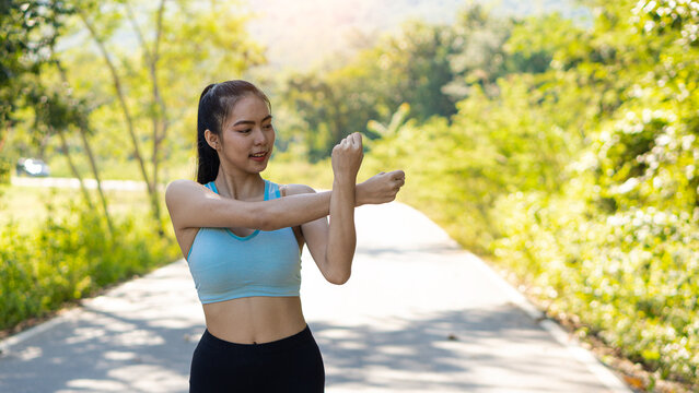 Asian women stretch before exercising for good health. Horizontal image while stretching in an outdoor park. A female runner warms up for an evening run and jogging.
