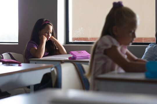 Caucasian elementary schoolgirls studying at desk in classroom