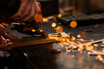 Close up Locksmith works with grinder machine, fly bright sparks. A man hand grinds a metal in...