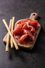 Spanish serrano ham with breadstick on black background