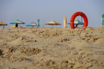 Fototapeta na wymiar Bright orange lifebuoy on a sandy beach
