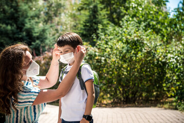 Family with kids in face mask going to school or kindergarten. Mother and child wear facemask during coronavirus and flu outbreak. Virus and illness protection, hand sanitizer in public crowded place