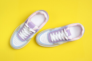 New colored sneakers with white laces on a yellow background. Trendy colorful photo minimal style. Top view, flat lay.