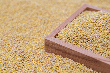 A background with millet stacked and a wooden bowl containing millet.