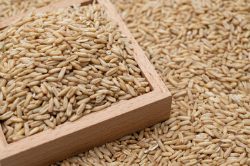 A background with oats stacked and a wooden bowl containing oats