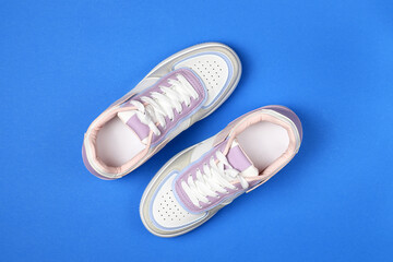 New colored sneakers with white laces on a blue background. Trendy colorful photo minimal style. Top view, flat lay.