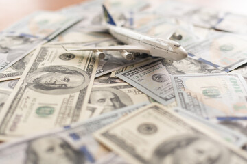 Airplane and dollars on a white background. Passenger airplane model on dollars and nearby. Business, air travel. Top and side view. Copy Space.