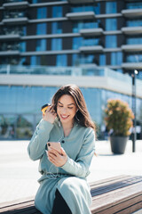 Fototapeta premium Beautiful business woman enjoying coffee break on free time outdoor with favorite music in earphones, millenial female listening audio book on mobile app
