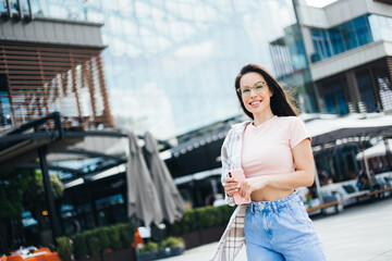Pretty young hipster female posing on street with smartphone, cute hipster fashionable woman with sexy body strolling outdoors