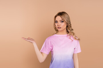 discouraged woman with wavy hair pointing with hand isolated on beige.