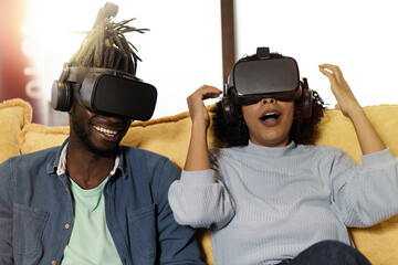 Amazed couple of multi-ethnic young people having fun playing video games with 360 vr 3d googles - lifestyle concept of friends having fun with tech gadgets - multiverse social media concept