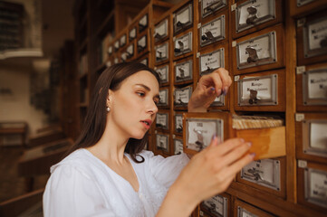 Attractive woman in a white blouse searches for information in the archives of the public library.