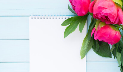 Bright pink peonies and a white notebook